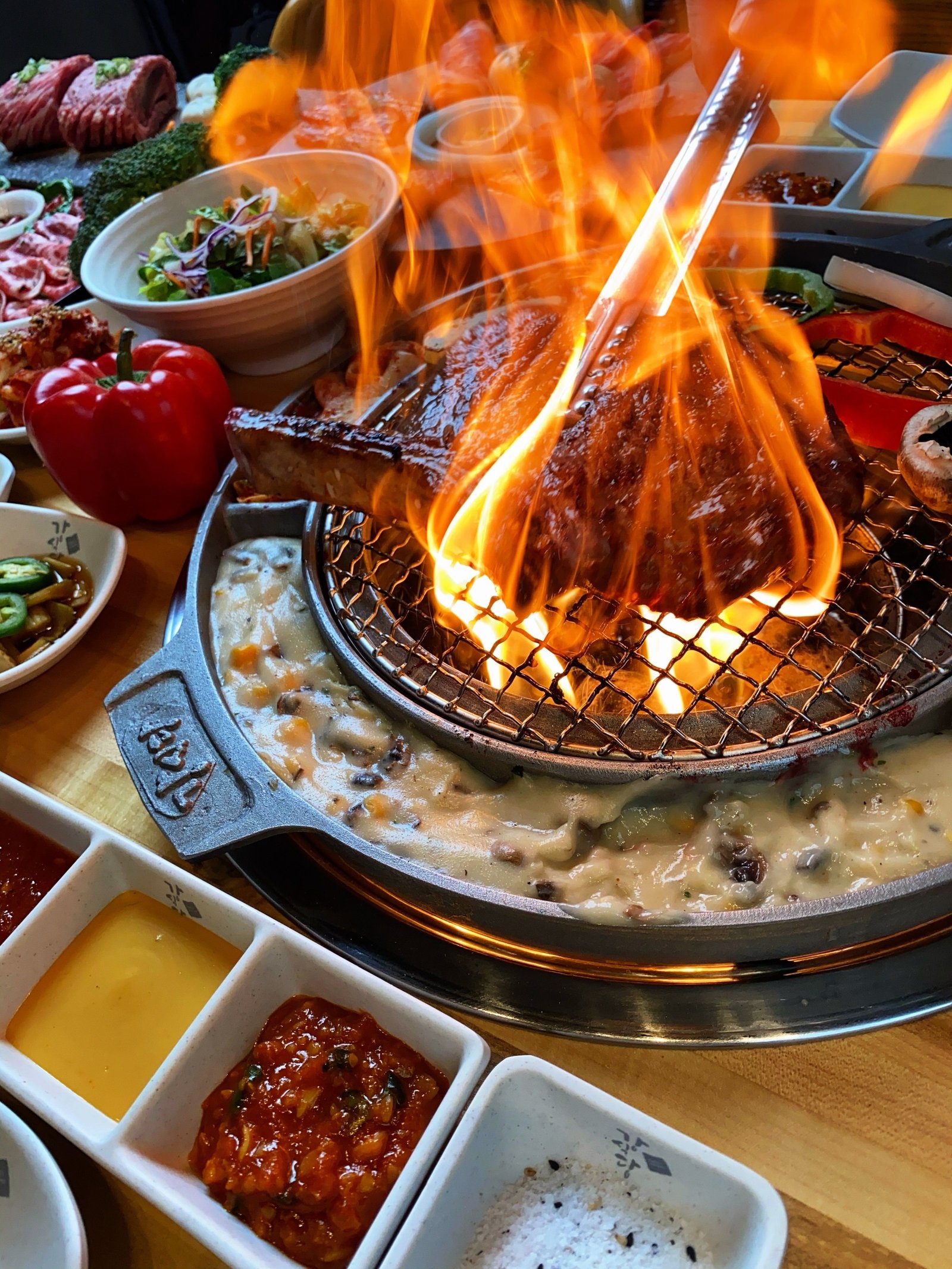 Beef searing in open flame at a table laid with banchan